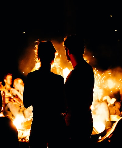 两个人站在篝火面前
